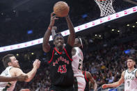 Toronto Raptors' Pascal Siakam grabs a rebound against Milwaukee Bucks' Jrue Holiday (21) during the second half of an NBA basketball game Thursday, Dec. 2, 2021, in Toronto. (Chris Young/The Canadian Press via AP)