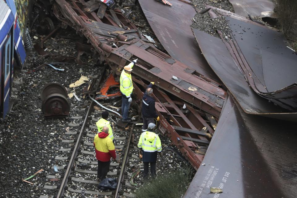 Workers stand on the rail lines after a collision in Tempe, about 376 kilometres (235 miles) north of Athens, near Larissa city, Greece, Thursday, March 2, 2023. Emergency workers are searching for survivors and bodies after a passenger train and a freight train crashed head-on in Tempe, central Greece just before midnight Tuesday. It was the country's deadliest rail crash on record. (AP Photo/Vaggelis Kousioras)