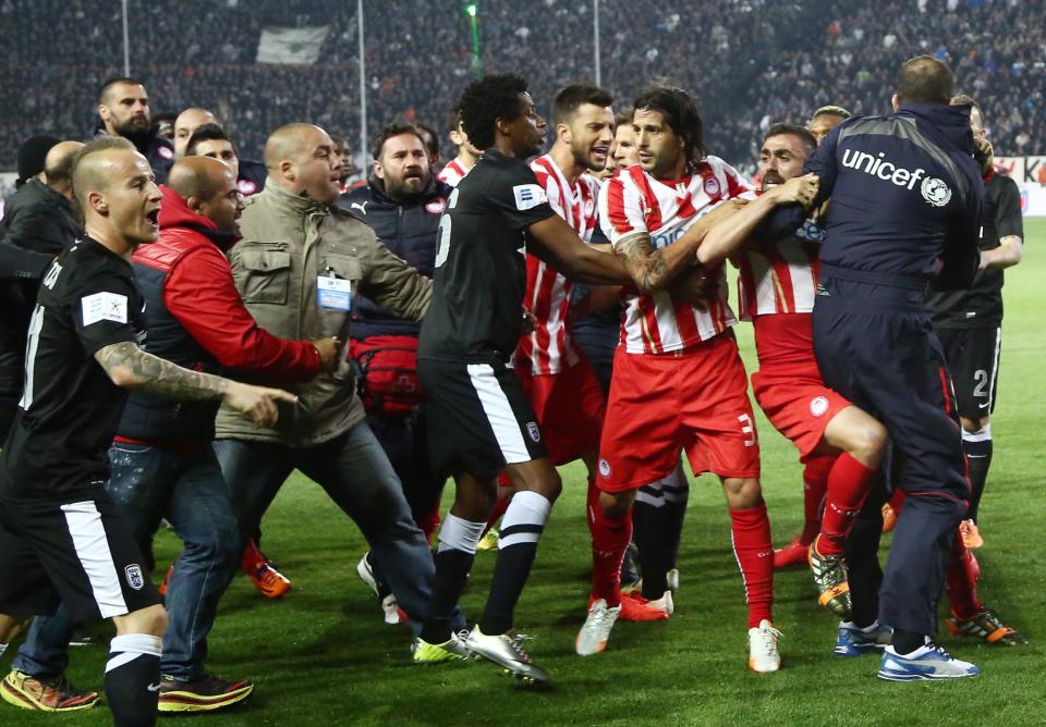 In this Wednesday, April 16, 2014 photo PAOK and Olympiakos players fight each other during a semi-final of the Greek Cup in the northern port city of Thessaloniki. Police in Thessaloniki have arrested a PAOK fan accused of dumping a crate of fish on the visiting Olympiakos bench, in a jibe that delayed a tense Greek cup semi-final for more than an hour. Another six PAOK supporters were arrested during clashes with police before and after Thursday’s match, which PAOK won 1-0 to advance on aggregate. The game was repeatedly halted by on-turf brawls, resulting in three red cards, while PAOK fans in the stands lit thousands of flares, and several were thrown on the pitch. (AP Photo/InTime Sports, Yorgos Matthaios) GREECE OUT