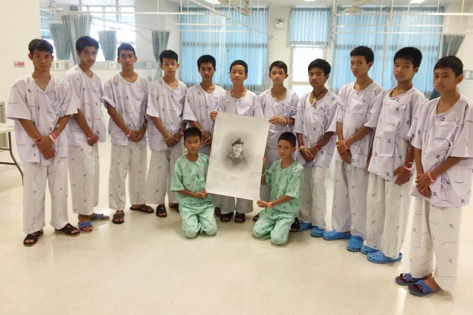 The rescued football team pose with a sketch of the Thai Navy SEAL diver who died while trying to rescue them: AP