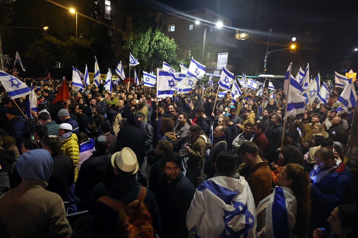 Demonstrators wave national flags during a rally against the Israeli government's judicial reforms outside Prime Minister Benjamin Netanyahu's residence in Jerusalem (AFP via Getty Images)