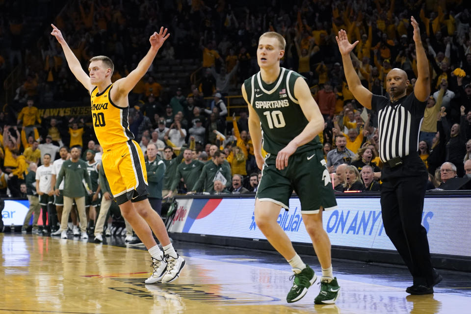Iowa forward Payton Sandfort (20) celebrates in front of Michigan State forward Joey Hauser (10) after making a 3-point basket at the end of an NCAA college basketball game, Saturday, Feb. 25, 2023, in Iowa City, Iowa. Iowa won 112-106 in overtime. (AP Photo/Charlie Neibergall)