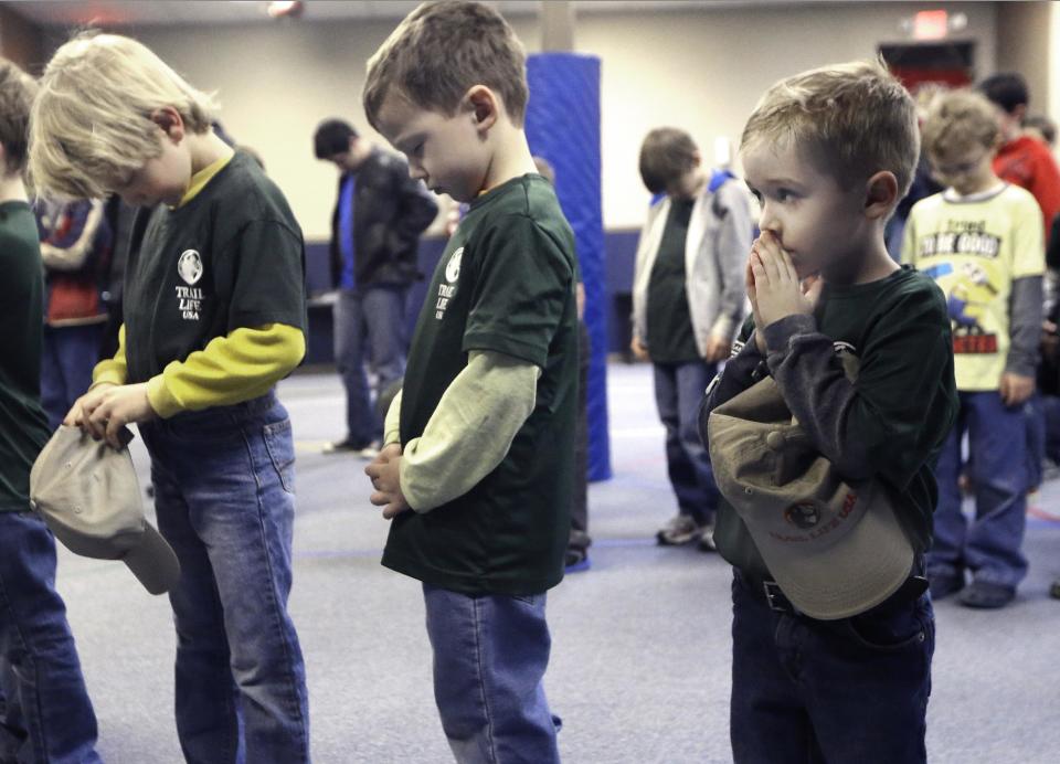 In this Tuesday, Feb. 4, 2014 photo, Trail Life members Malachi Glaspell, 5, right, prays with Layton Young, 6, center, Jack Eversole and other members during a meeting in North Richland Hills, Texas. The Trail Life USA oath calls on the boys in part "to serve God and my country, to respect authority, and to be a good steward of creation." (AP Photo/LM Otero)