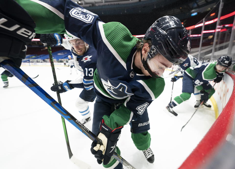 Vancouver Canucks defenseman Quinn Hughes (43) fights for control of the puck with Winnipeg Jets center Pierre-Luc Dubois (13) during second-period NHL hockey game action in Vancouver, British Columbia, Sunday, Feb. 21, 2021. (Jonathan Hayward/The Canadian Press via AP)