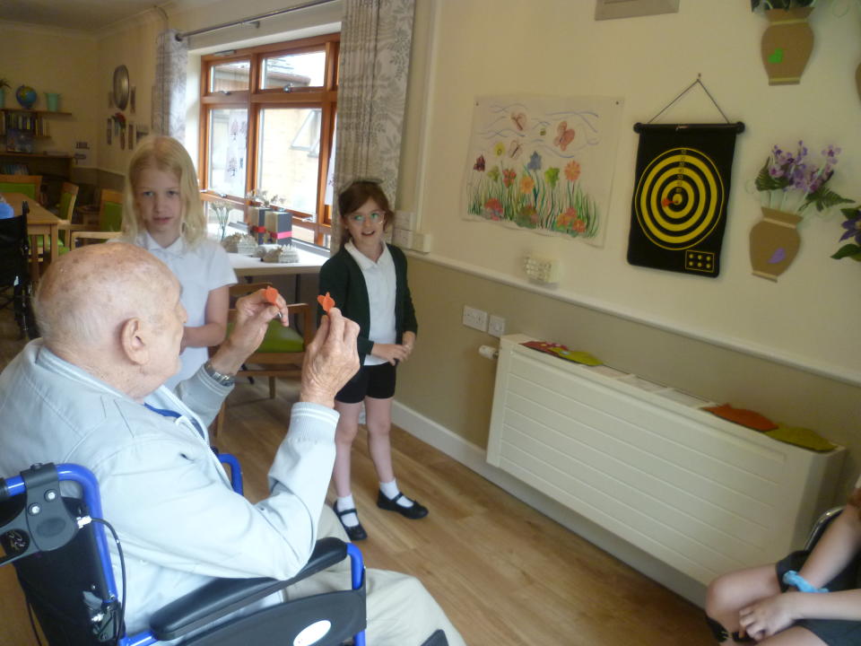 Man playing darts and girls looking at him 