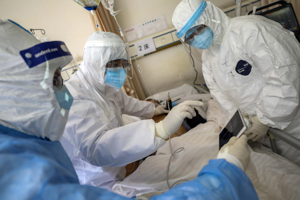 In this Sunday, Feb. 16, 2020, photo, medical personnel scan a new coronavirus patient at a hospital in Wuhan in central China's Hubei province. Chinese authorities on Monday reported a slight upturn in new virus cases and hundred more deaths for a total of thousands since the outbreak began two months ago. (Chinatopix via AP)