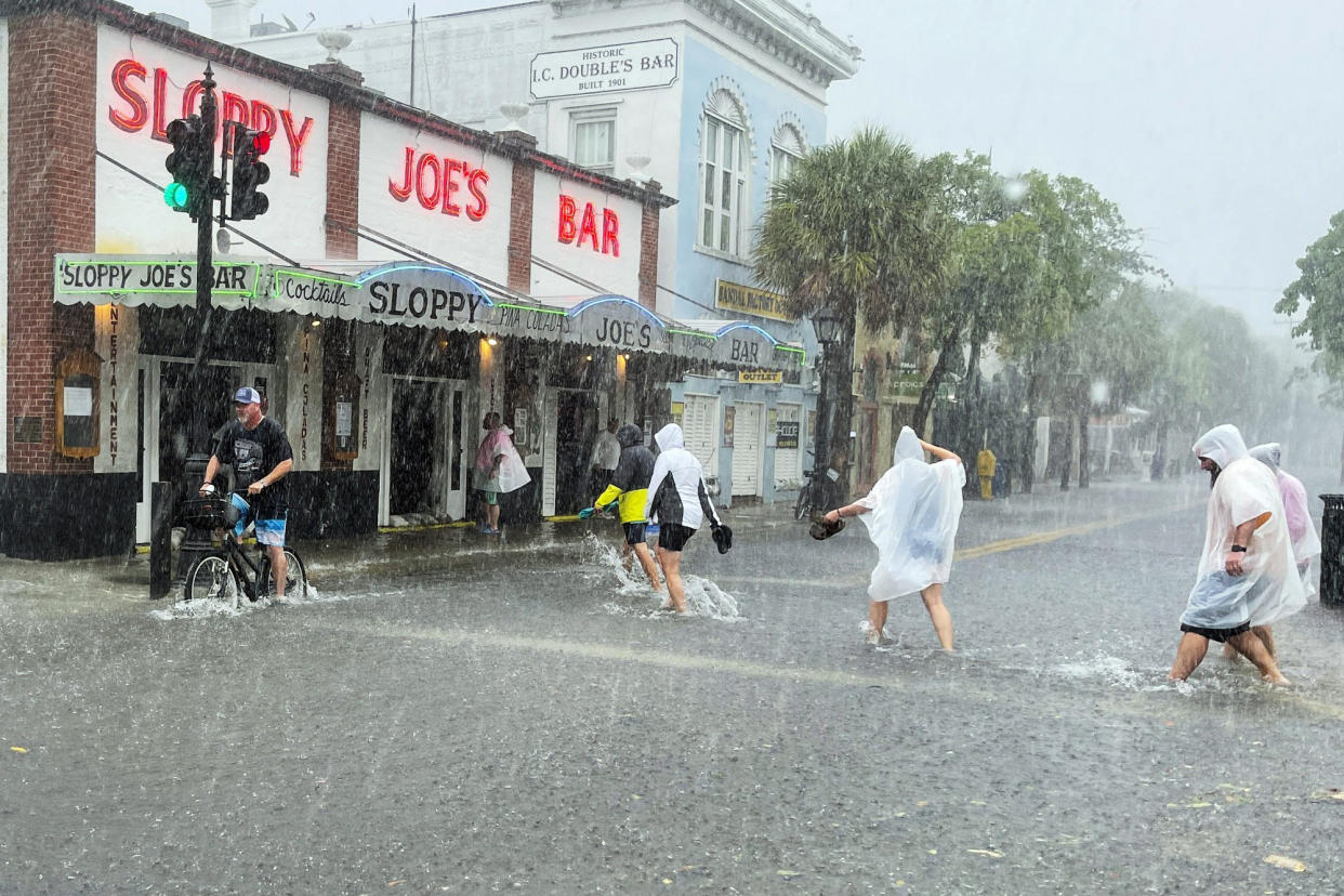 Determined visitors head for Sloppy Joe's Bar while crossing a flooded Duval Street as heavy winds and rain pass over Key West, Fla., on July 6, 2021. (Rob O'Neal / AP)