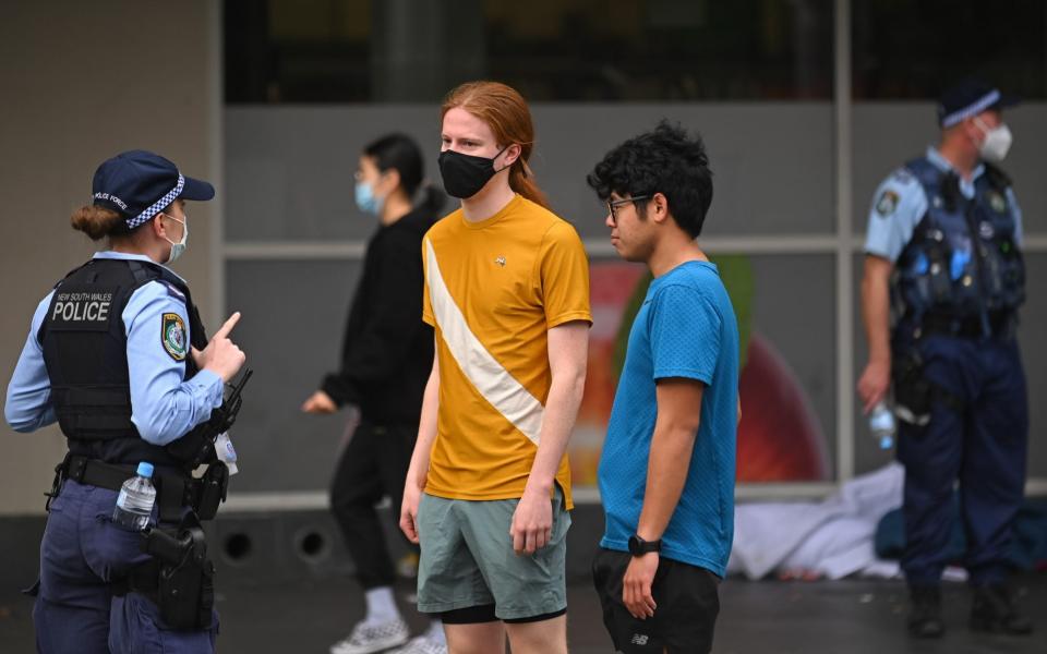 Police officers check ID cards of people walking in the CBD in order to prevent an anti-lockdown protest, during lockdown in Sydney, Australia, Saturday, July 31, 2021. - Anadolu