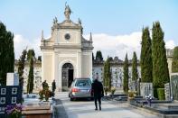 Un hombre camina en solitario detrás del vehículo que lleva los restos de su madre antes de la celebración de un funeral en el cementerio de Seriate, que permanece cerrado. (PIERO CRUCIATTI/AFP via Getty Images)