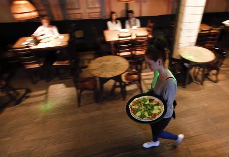A waitress serves pizza at a restaurant in Moscow, September 10, 2014. REUTERS/Maxim Zmeyev