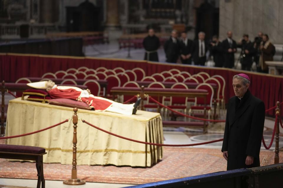 The body of late Pope Emeritus Benedict XVI laids out in state as father Georg Gaenswein stands on the right inside St. Peter's Basilica at The Vatican, Monday, Jan. 2, 2023. Benedict XVI, the German theologian who will be remembered as the first pope in 600 years to resign, has died, the Vatican announced Saturday. He was 95. (AP Photo/Andrew Medichini)