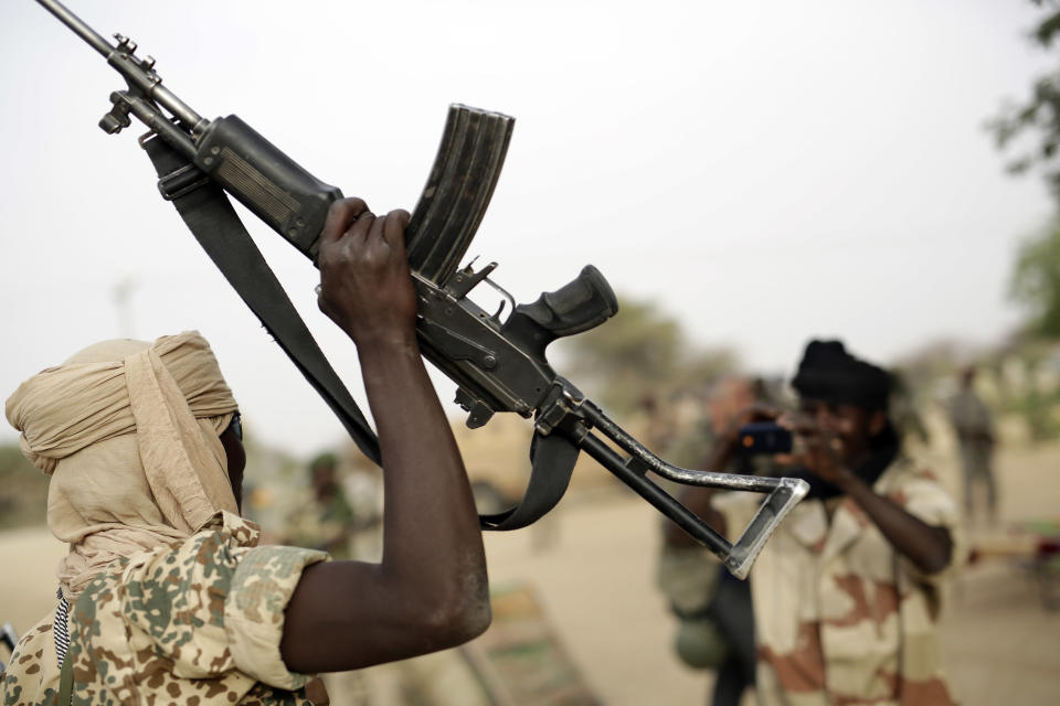 A Chadian soldier raises his automatic weapon to have his picture taken by another soldier  in the Nigerian city of Damasak, Nigeria, Wednesday March 18, 2015.  (AP Photo/Jerome Delay)