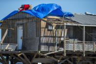 A man attaches a tarp to a damaged building Thursday, Oct. 29, 2020, as Cocodrie, La., residents try to repair their homes hit by Hurricane Zeta. Residents slowly returned to their homes and fishing camps to assess the damage left by the storm. (Chris Granger/The Advocate via AP)