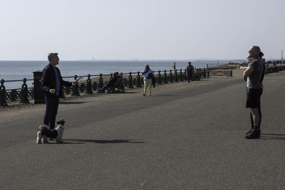 People engage in conversation while adhering to the Government's advice of keeping 2 metres away from each other while on the seafront in Brighton, East Sussex, as the UK continues in lockdown to help curb the spread of Coronavirus.