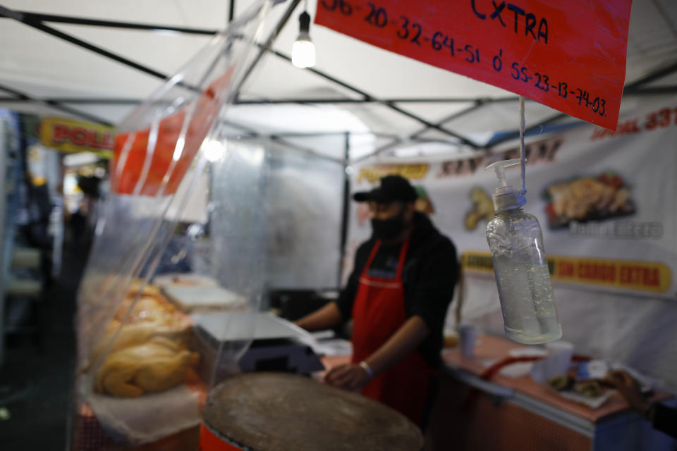 A bottle of antibacterial gel for the use of clients hangs from a cord next to a chicken seller in Mercado San Cosme, where some vendors put in place their own protective measures against coronavirus while others continue to work without masks or barriers, in Mexico City, Thursday, June 25, 2020. (AP Photo/Rebecca Blackwell)