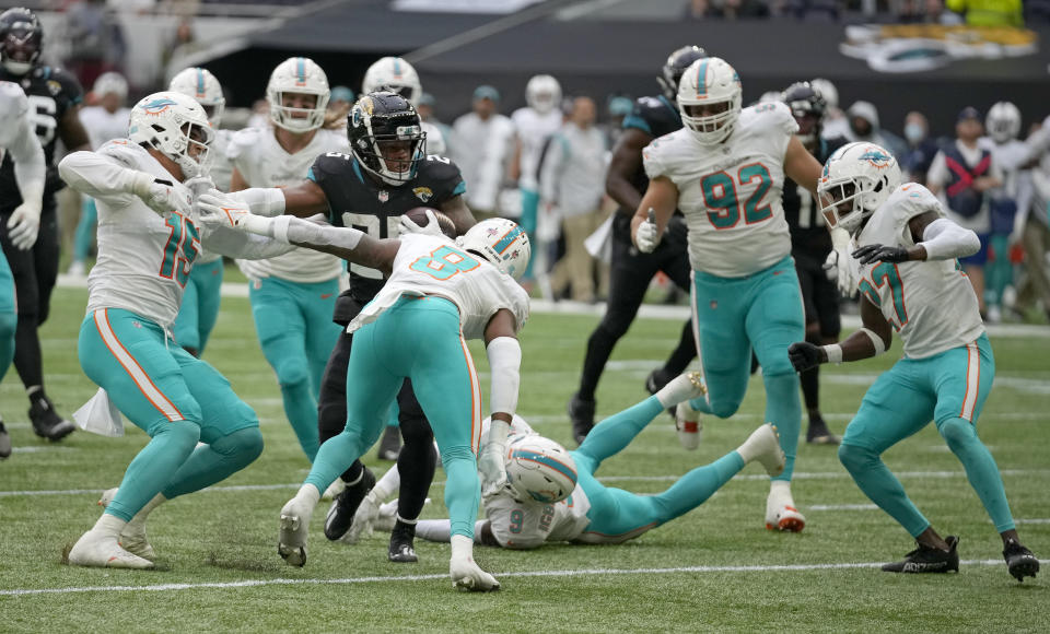 Jacksonville Jaguars running back James Robinson (25), center, makes yards on a drive that would end in a touchdown during the second half of an NFL football game between the Miami Dolphins and the Jacksonville Jaguars at the Tottenham Hotspur stadium in London, England, Sunday, Oct. 17, 2021. (AP Photo/Matt Dunhan)