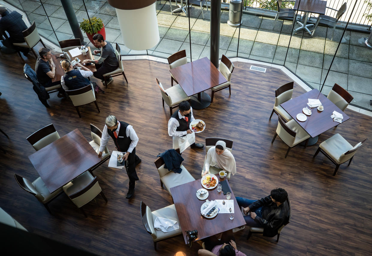 A server brings food to a table as people dine at a restaurant in Vancouver, on Tuesday, September 21, 2021. As hotel and restaurant owners increasingly turn to temporary foreign workers to fill labour gaps, there are growing calls to give those workers more paths to permanent residency. THE CANADIAN PRESS/Darryl Dyck