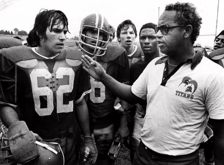File= This 1971 file photo shows Alexandria, Va's., T.C. Williams High School football coach Herman Boone, right, during a break at summer camp, with guard Johnny Colantuoni, (62) and John Vaughn, center. Boone, the Virginia high school football coach who inspired the movie "Remember the Titans," has died. He was 84. Boone guided T.C. Williams High School to a state championship while navigating the early days of desegregation. Aly Khan Johnson, an assistant coach for Boone beginning in 1972, said the coach died Wednesday, Dec. 18, 2019, at his home In Alexandria, Va. Johnson said a funeral home operated by his wife is handling the arrangements, which are not complete. (AP Photo/File)