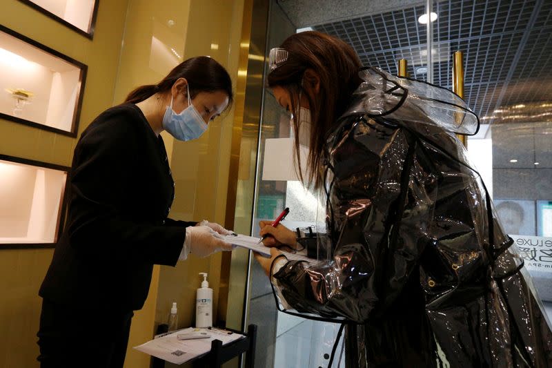 A customer wearing a raincoat, a face mask and goggles registers as she arrives at the Pearl Deluxe beauty spa for facial treatment, as the country is hit by an outbreak of the novel coronavirus, in Beijing