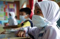 Students cover their faces with masks at a school as haze shrouds Kuala Lumpur