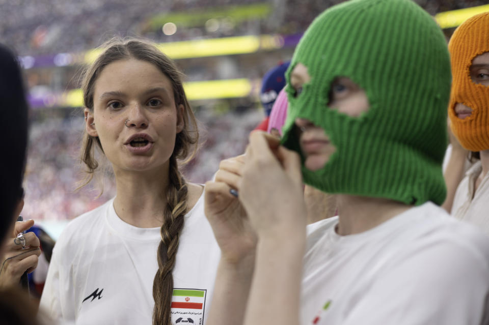 A group of young women, some, wearing colorful balaclavas who identified themselves as members of the Pussy Riot collective in the stands during the World Cup group B soccer match between Iran and the United States at the Al Thumama Stadium in Doha, Qatar, Tuesday, Nov. 29, 2022. (AP Photo/Ciaran Fahey)