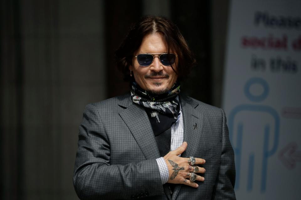 Johnny Depp gestures to fans and the media as he arrives at the High Court in London on Aug. 9.