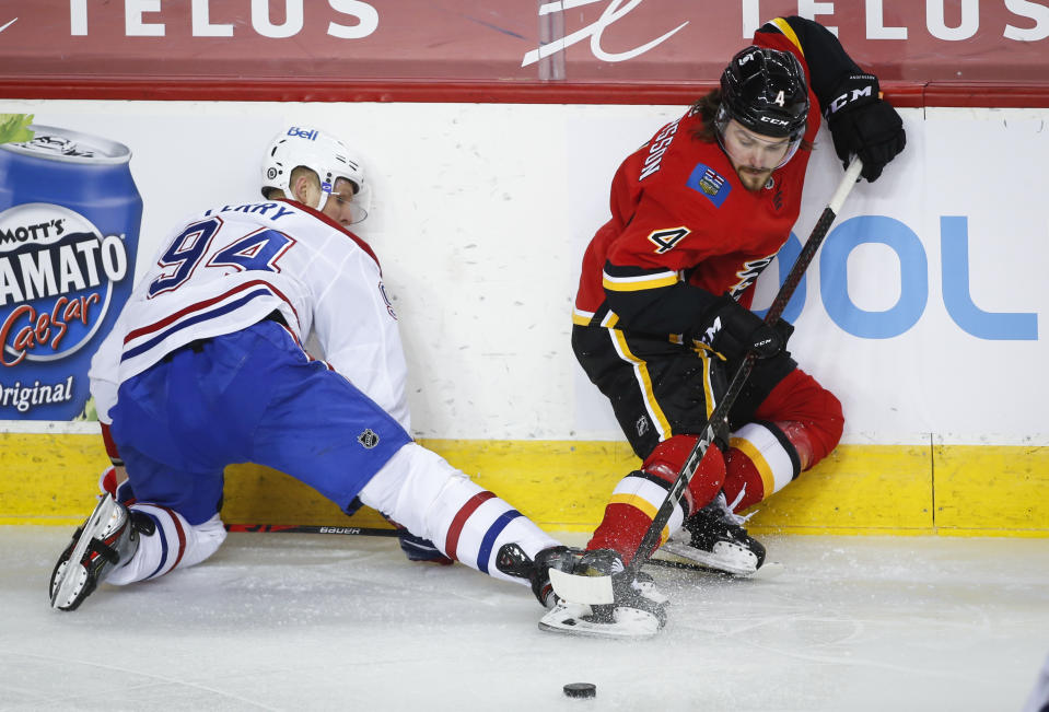 Montreal Canadiens' Corey Perry, left, tries to kick the puck away from Calgary Flames' Rasmus Andersson during second-period NHL hockey game action in Calgary, Alberta, Friday, April 23, 2021. (Jeff McIntosh/The Canadian Press via AP)