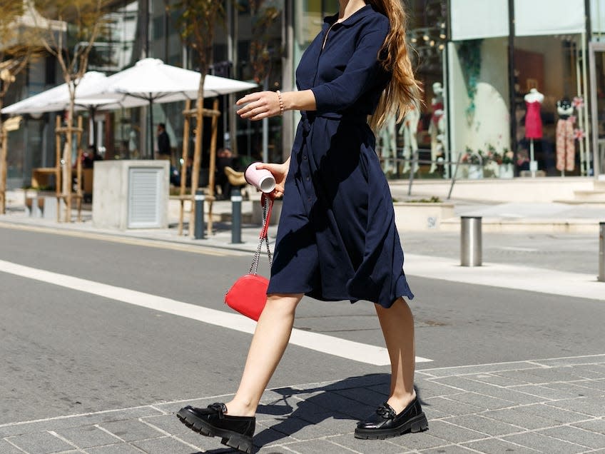 woman crossing a street wearing a nice navy blue dress