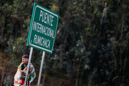 A Venezuelan migrant leans against a sign that reads "Rumichaca International Bridge", at the Rumichaca International Bridge, Ecuador August 18, 2018. REUTERS/Luisa Gonzalez