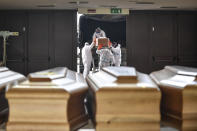 Coffins arriving from the Bergamo area, where the coronavirus infections caused many victims, are being unloaded from a military truck that transported them in the cemetery of Cinisello Balsamo, near Milan in Northern Italy, Friday, March 27, 2020. The new coronavirus causes mild or moderate symptoms for most people, but for some, especially older adults and people with existing health problems, it can cause more severe illness or death. (Claudio Furlan/LaPresse via AP)
