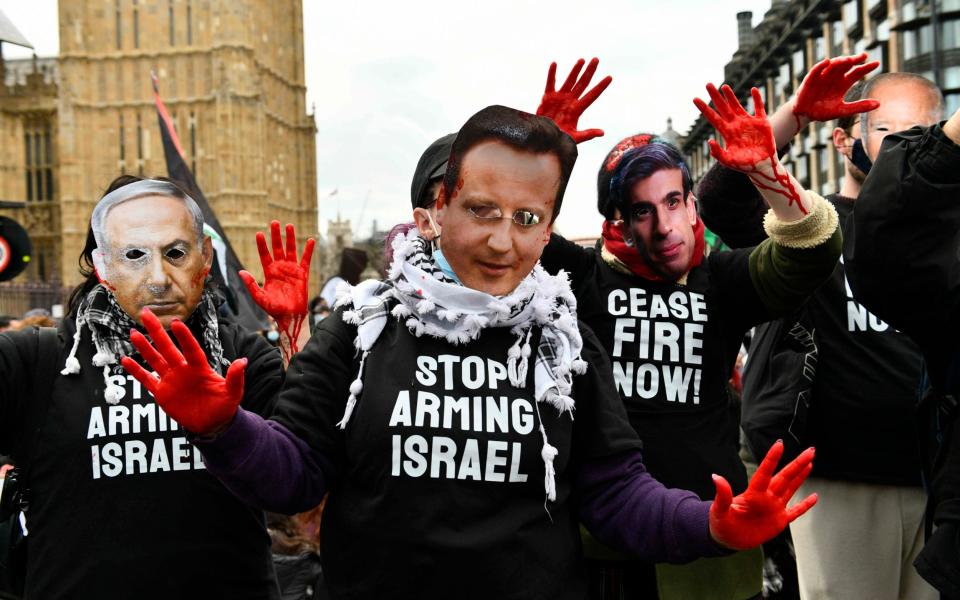 Activists wear masks of politicians' faces, including Rishi Sunak and David Cameron