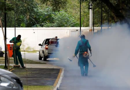 A truck sprays insecticide near grounds workers at Olympic media accomodations as part of preventive measures against the Zika virus and other mosquito-borne diseases, in Rio de Janeiro, Brazil August 29, 2016. REUTERS/Chris Helgren