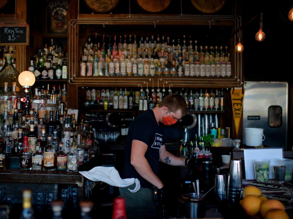 A bartender wearing a facemask and gloves makes drinks at Eight Row Flint in Houston, Texas, on May 22, 2020, amid the novel coronavirus pandemic.