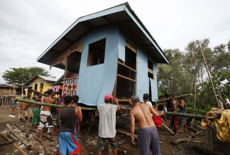 Residents lift a house damaged by Typhoon Rammasun (locally named Glenda) in a coastal village of sea gypsies, also known as Badjaos, in Batangas city, south of Manila, July 17, 2014. REUTERS/Erik De Castro