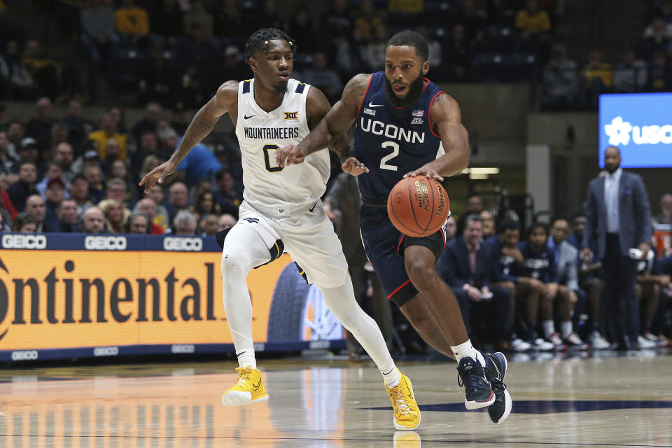 Connecticut guard R.J. Cole (2) is defended by West Virginia guard Kedrian Johnson (0) during the first half of an NCAA college basketball game in Morgantown, W.Va., Wednesday, Dec. 8, 2021. (AP Photo/Kathleen Batten)