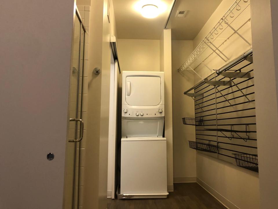 the walk in closet with bathroom and washer/dryer in the back