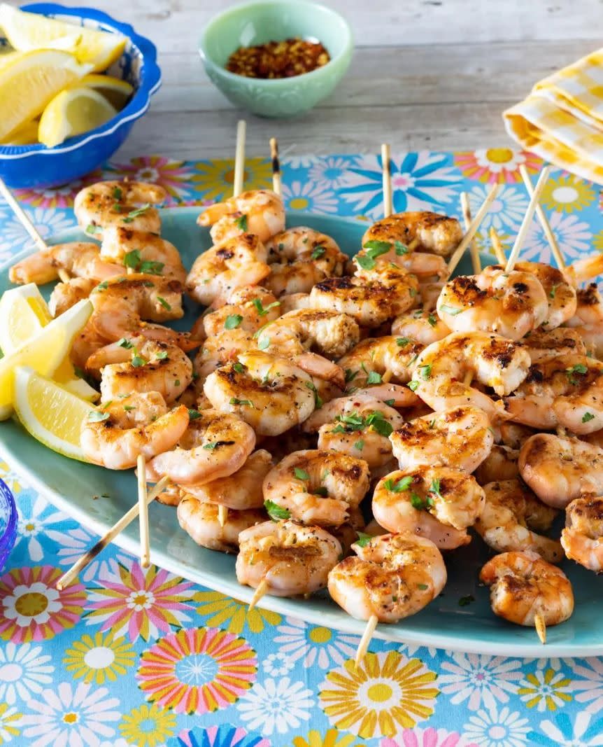 grilled shrimp skewers with lemon wedges on floral tablecloth