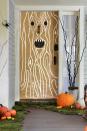 <p>Trick out your front porch with a layer of moss, spiderwebs and critters—plus a menacing tree trunk on the door. <strong><br></strong></p><p><strong>Make the Doorway:</strong> Use painter's tape to attach brown kraft paper to your door, cutting slits for the handle and knocker. Cut eyes and a mouth out of black construction paper; tape to kraft paper with double-sided tape. For the wood grain: Take white craft paint and draw curved lines first around the facial features, then vertically on the door. Place preserved green moss along the edges of your front steps or porch. Top with pumpkins.</p>