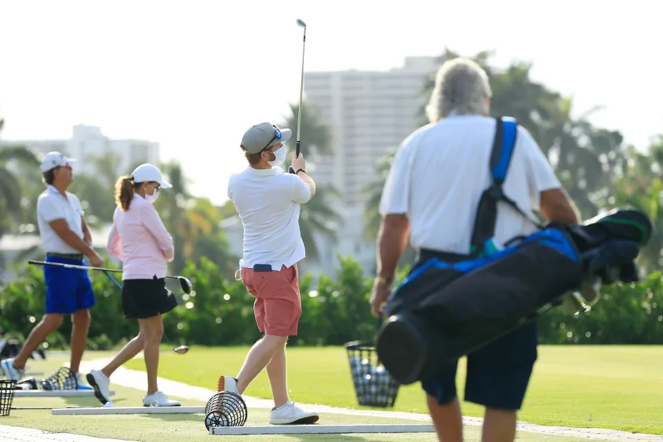 MIAMI BEACH, FLORIDA - APRIL 29: Players wearing face masks warm up on the range at the Miami Beach Golf Club on April 29, 2020 in Miami Beach, Florida.  The city of Miami Beach partially reopened parks and facilities including golf courses, tennis courts and marinas as it begins easing restrictions made due to the COVID-19 pandemic. (Photo by Cliff Hawkins/Getty Images)