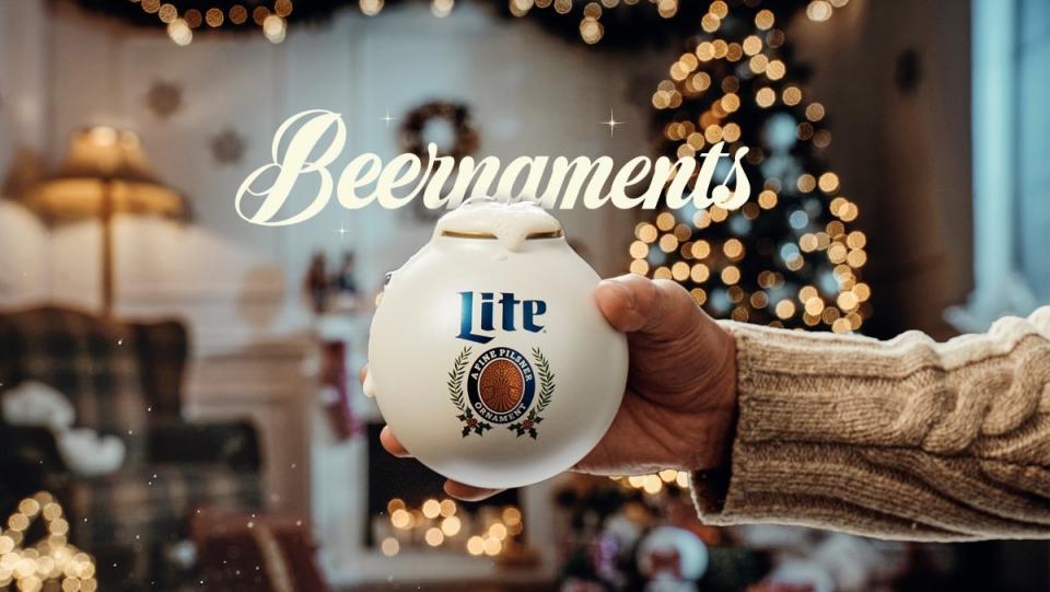 A hand holding a Miller Lite ornament that holds a 12 ounce can of beer