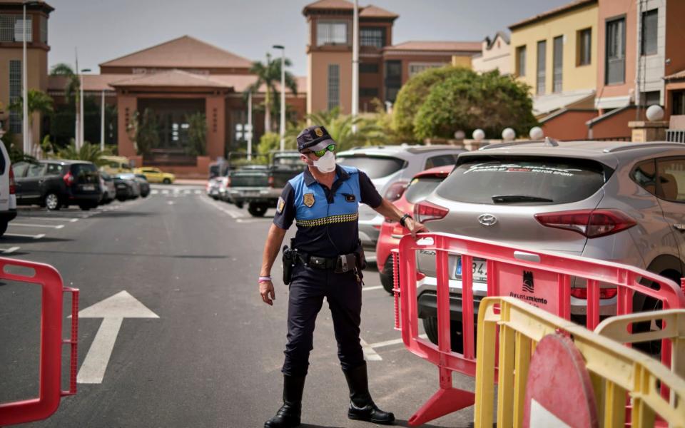 A Spanish police officer sets a barrier blocking access to the H10 Costa Adeje Palace hotel in Tenerife - AP