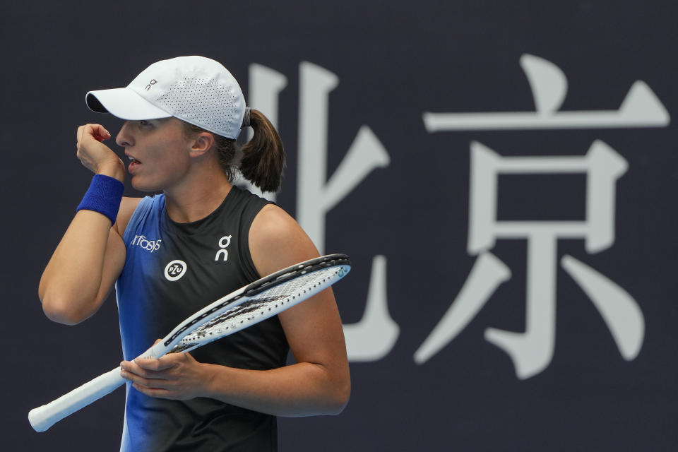 Iga Swiatek of Poland wipes her sweat during the first round of the women's singles match against Sara Sorribes Tormo of Spain in the China Open tennis tournament at the Lotus Court in Beijing, Monday, Oct. 2, 2023. (AP Photo/Andy Wong)