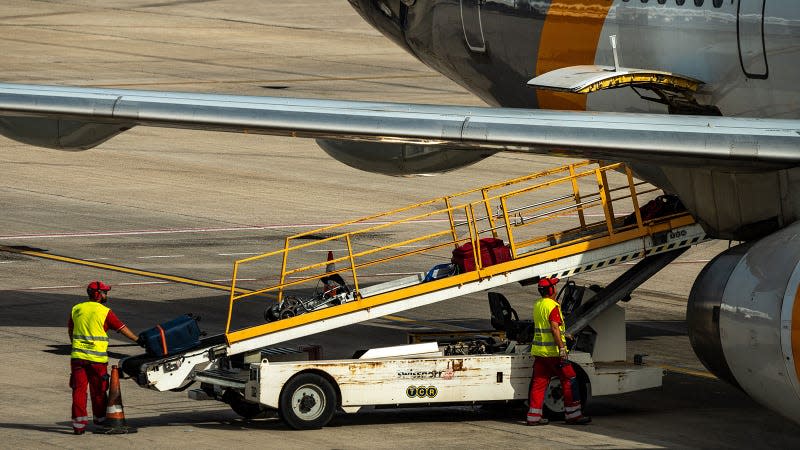 A photo of workers loading luggage into a plane. 