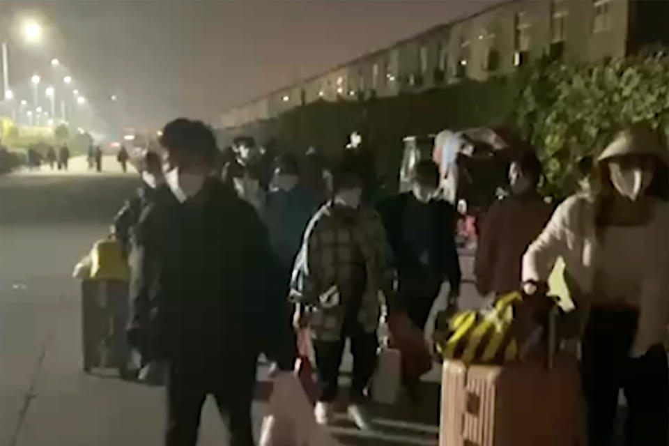 FILE - In this photo taken from video footage and released by Hangpai Xingyang, people with suitcases and bags are seen leaving from a Foxconn compound in Zhengzhou in central China's Henan Province on Oct. 29, 2022. Employees at the world's biggest Apple iPhone factory have been beaten and detained in protests over contract disputes amid anti-virus controls, according to employees and videos posted on social media Wednesday, Nov. 23, 2022. (Hangpai Xingyang via AP, File)