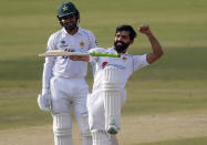 Pakistan's Fawad Alam, right, celebrates after scoring century while his teammate Faheem Ashraf watches during the second day of the first cricket test match between Pakistan and South Africa at the National Stadium, in Karachi, Pakistan, Wednesday, Jan. 27, 2021. (AP Photo/Anjum Naveed)