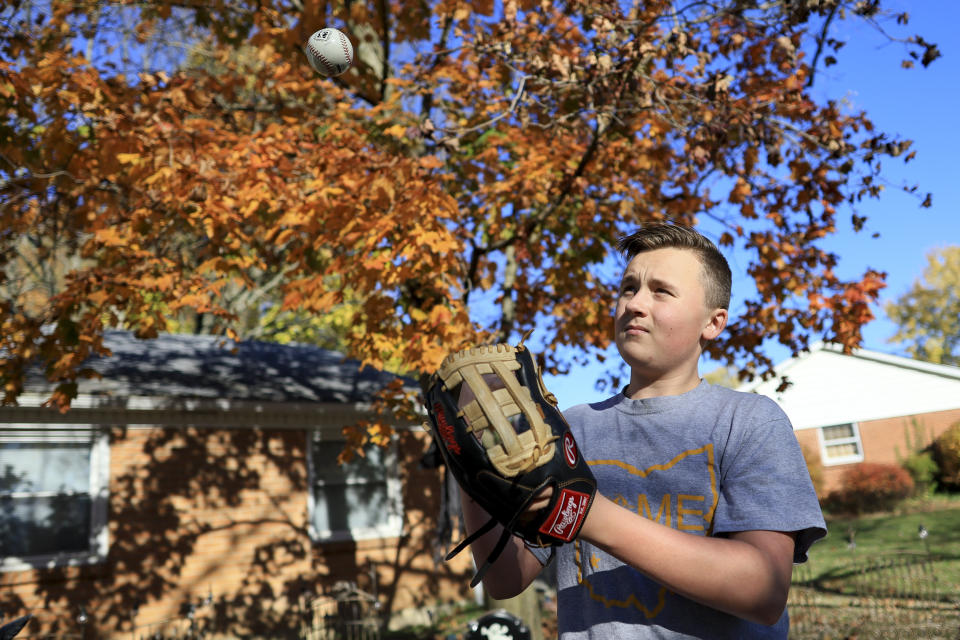Liam Kennedy tosses a baseball he stands in his family's front yard Friday, Oct. 28, 2022, in Monroe, Ohio. (AP Photo/Aaron Doster)