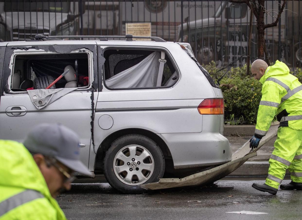 Cleanup crews remove debris lodged underneath a van in Montebello.