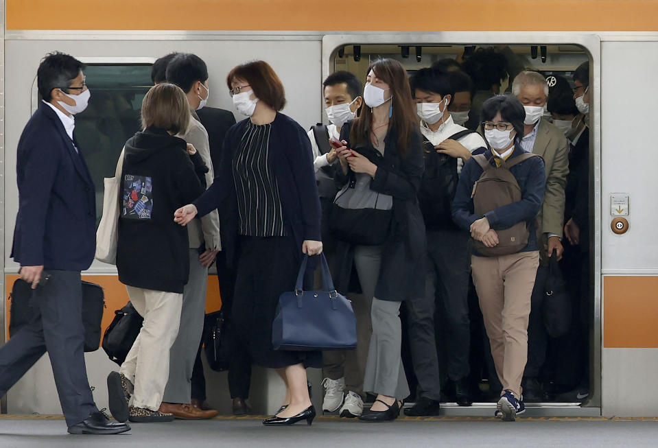 Commuters step out of a train at a station in Tokyo Thursday, May 6, 2021. Tokyo is under a state of emergency with coronavirus infections rising, particularly new variants. The state of emergency is to expire on May 11, but reports in Japan say it is likely to be extended. (Shinji Kita/Kyodo News via AP)