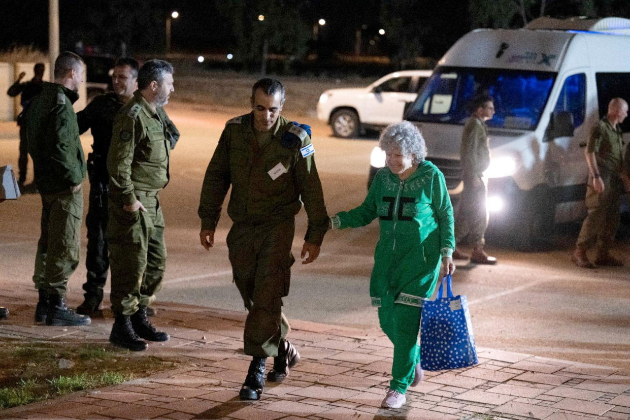 A smiling woman walks with a soldier.