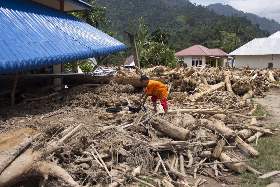 Un menor sube en troncos arrastrados en un barrio afectado por una inundación repentina en Pesisir Selatan, en Sumatra Occidental, Indonesia, el miércoles 13 de marzo de 2024. (AP Foto/Mavendra JR)